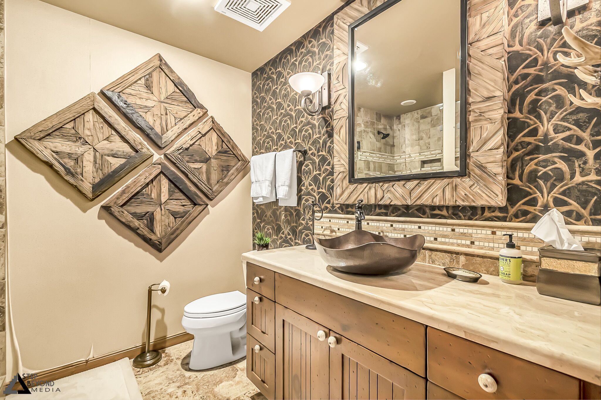 A bathroom with a wooden vanity, a large mirror, and a decorative wall panel.