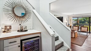 Una cocina moderna con refrigerador empotrado, un espejo con diseño radiante y un comedor con vistas al exterior.