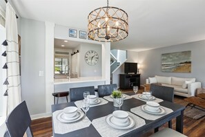 Enjoy meals in this stylish dining area with a table for four, a sofa, and a beautiful beach scene painting.