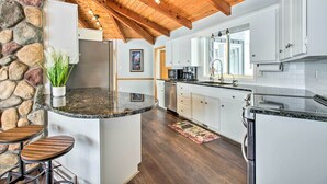 Una cocina moderna con una pared de detalles en piedra, vigas de madera en el techo y encimera de granito.