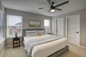 A bedroom with a bed, two bedside tables, a ceiling fan, and two doors.