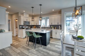 A modern kitchen with white cabinets, a central island, and two bar stools.