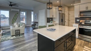 Una cucina moderna con una grande isola, elettrodomestici in acciaio inossidabile e una ventola a soffitto.