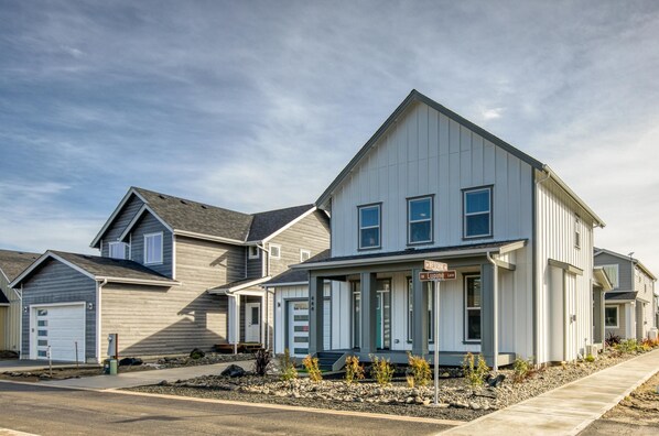 A modern two-story residential building with a prominent front porch and a garage.
