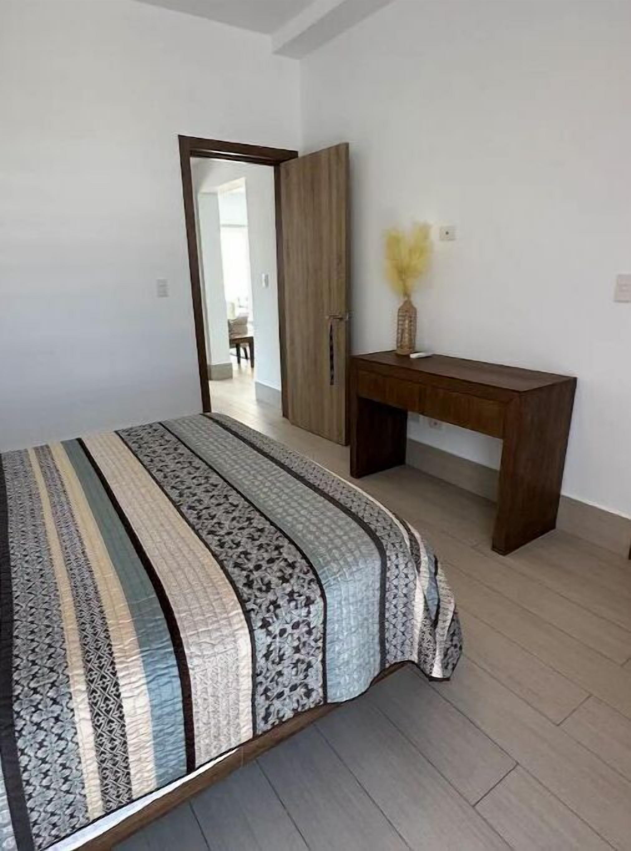 Un dormitorio con cama, un escritorio de madera y un armario.