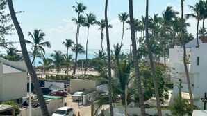Un quartier résidentiel bordé de palmiers, où l’on peut voir des voitures garées et d’où l’on a une vue sur la plage.
