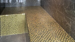 Un baño moderno con paredes de mármol oscuro y piso de baldosas.