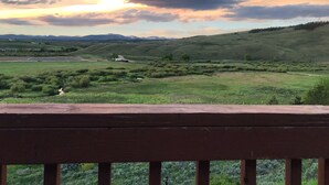Una vista panorámica de un paisaje con praderas, colinas ondulantes y una cadena montañosa distante.