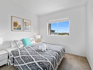 Une chambre à coucher comprenant un lit, une table de chevet, une fenêtre et deux tableaux accrochés au mur.