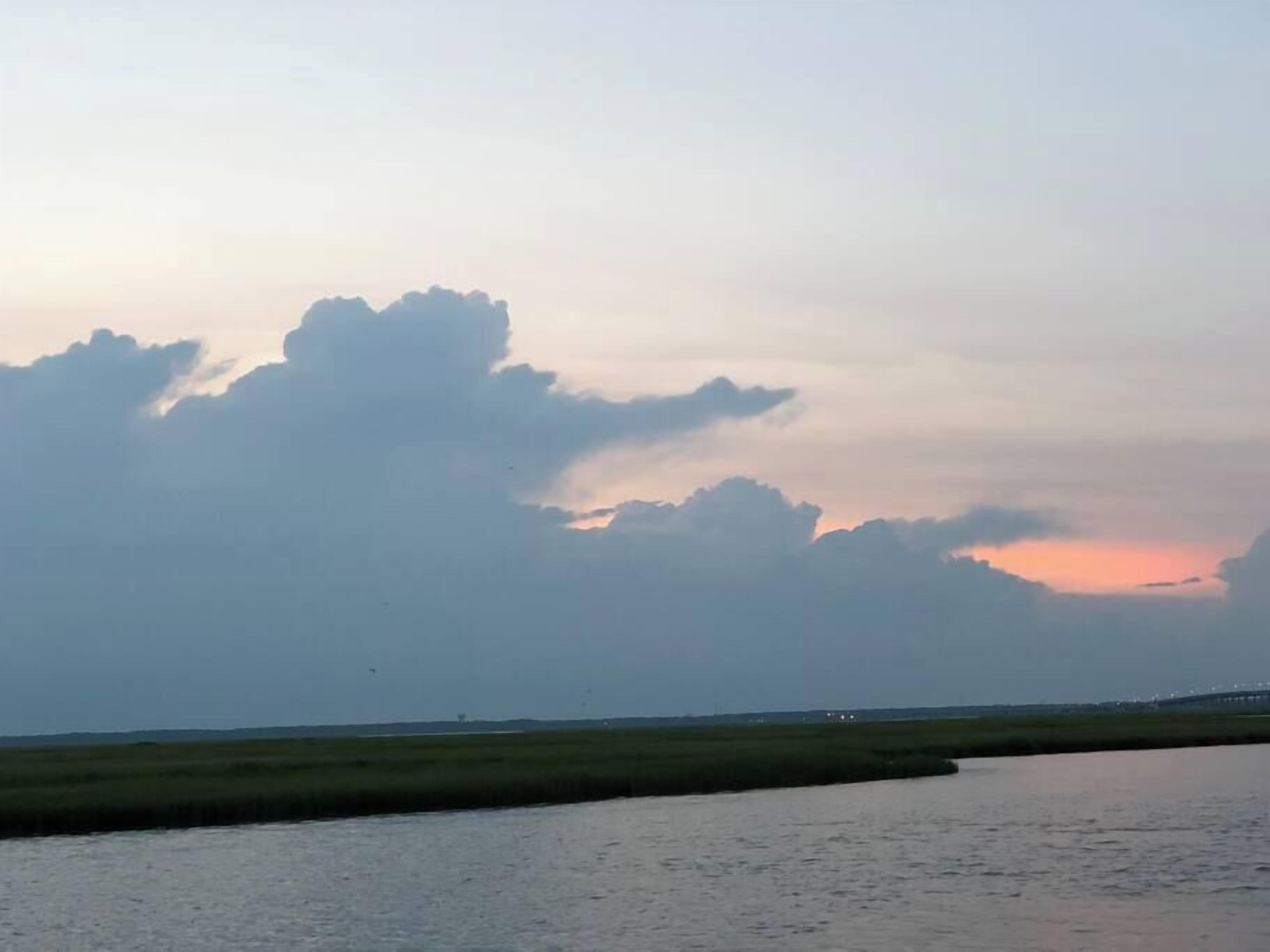 A calm river with a distant bridge and a cloudy sky.