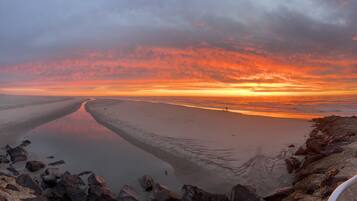 Une plage avec une mer calme, un ciel dégagé et un coucher de soleil.