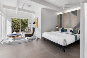 Un dormitorio moderno con una cama grande, un escritorio y una silla, con vista a zonas verdes.