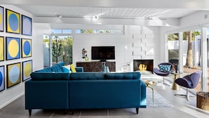 A modern living room with a blue sofa, a flat-screen TV, and a fireplace.