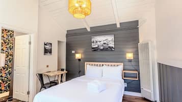 Quarto com cama, mesa de cabeceira, luminária e ar-condicionado fixado na parede.