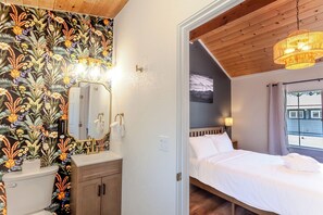 A bedroom with a bed, a bedside table, a window with curtains, and a view of the outside. - Tahoe Mountain inn (South Lake Tahoe)