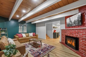 A living room with a fireplace, a sofa, a coffee table, and a patterned rug. - Tahoe Mountain inn (South Lake Tahoe)