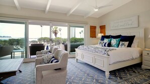 A bedroom with a bed, a chair, a nightstand, and a view through a sliding door.