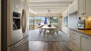 A modern kitchen with a stainless steel refrigerator, a built-in oven, and a dining area with a table and chairs.