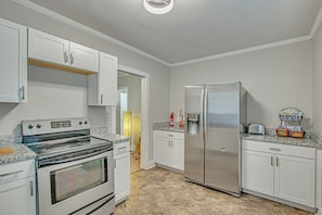A kitchen with white cabinets, a stainless steel refrigerator, a built-in oven, and granite countertops.