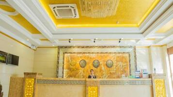 A reception area with a marble counter, a chandelier, and a wall clock.