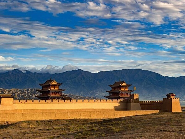 A traditional Chinese-style building with a prominent wall and a mountainous backdrop. - Greentree Inn Jiayuguan Xinhua Nan Road (Jiayuguan)