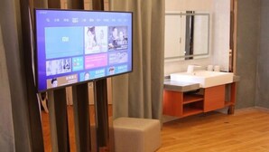 A modern hotel room with a flat-screen TV displaying a streaming service interface, a wooden floor, and a bathroom with a vanity and sink. - Shell Shanghai Wanda Square Wujiaochang Metro Station Hotel (Shanghai)