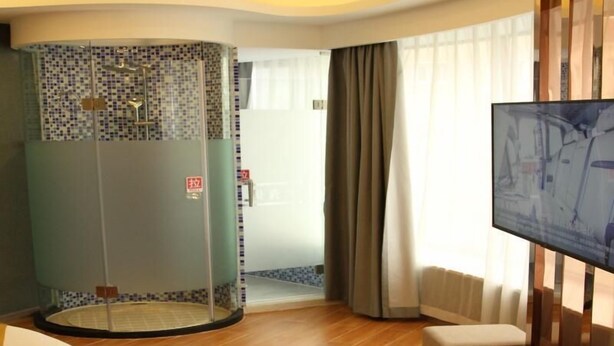 A hotel room with a shower area, a television, and a seating area with a view of the outdoors. - Shell Shanghai Wanda Square Wujiaochang Metro Station Hotel (Shanghai)