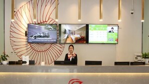 A hotel reception desk with a large screen displaying a racing car and a bed. - Shell Shanghai Wanda Square Wujiaochang Metro Station Hotel (Shanghai)