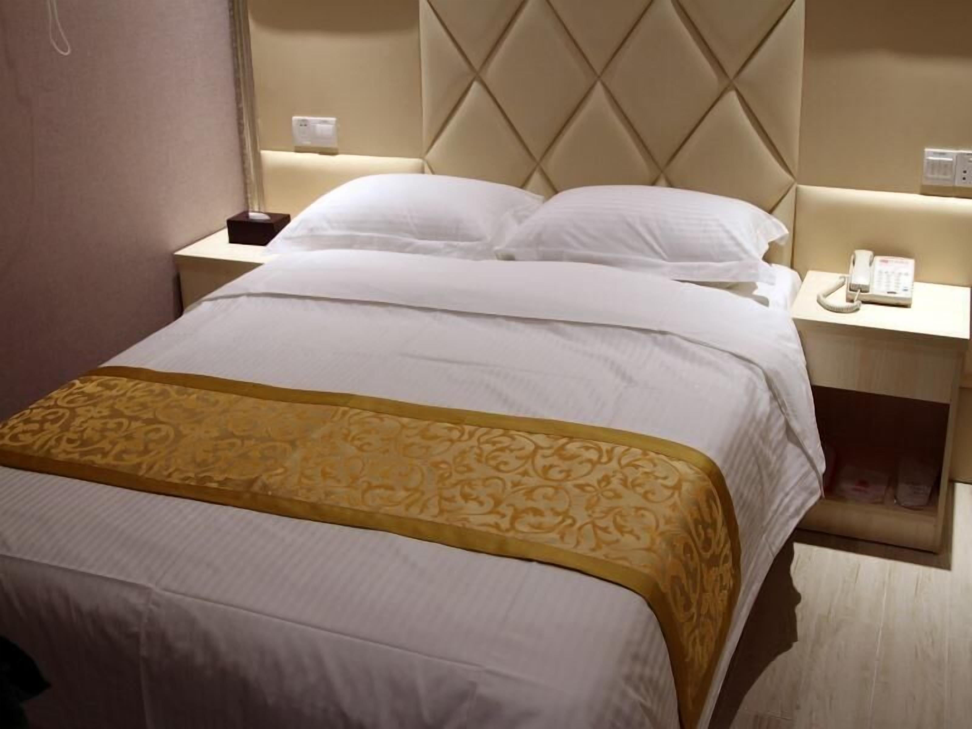 Une chambre d’hôtel avec un grand lit, une table de chevet avec un téléphone et une lampe fixée au mur.