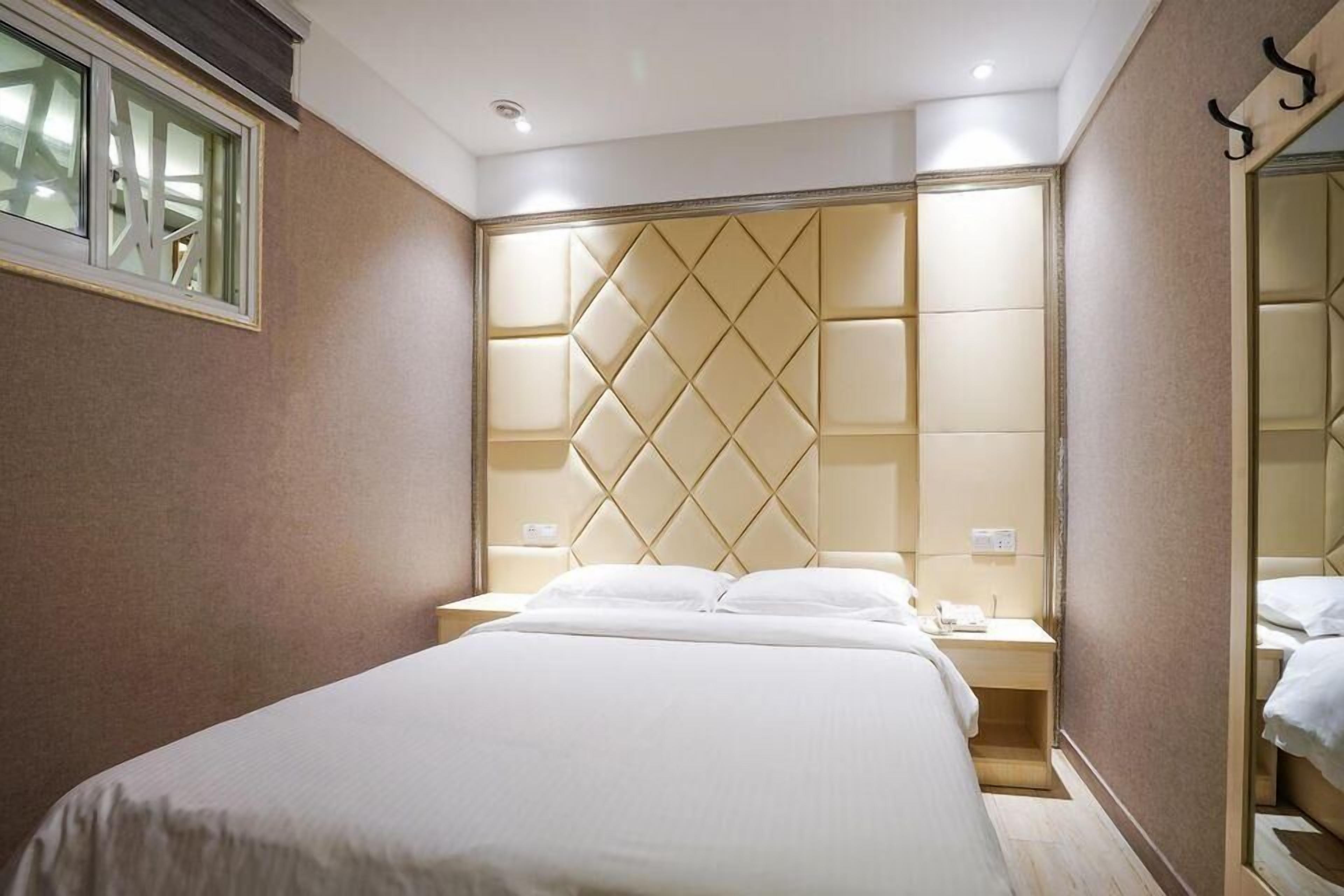 Ein Hotelzimmer mit einem großen Bett, einem Kopfteil mit Rautenmuster, Nachttischen und einem Spiegel.