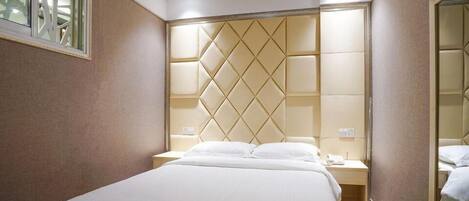 Ein Hotelzimmer mit einem großen Bett, einem Kopfteil mit Rautenmuster, Nachttischen und einem Spiegel.