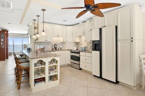 Enjoy cooking in this well-equipped kitchen with a central island and bar stools, featuring stainless steel appliances and pendant lighting.