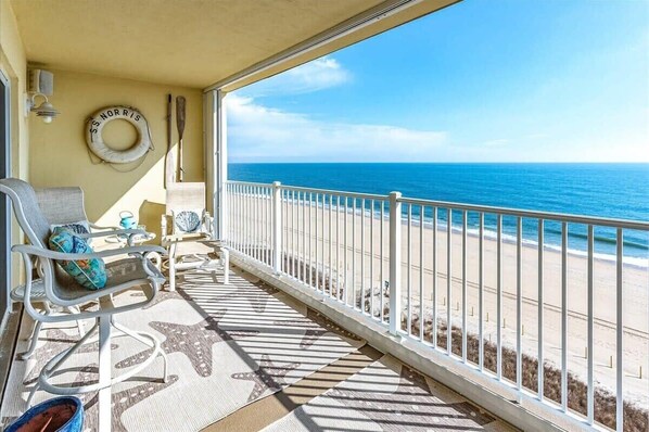 Enjoy the ocean view from this balcony with a chair, table, and life ring.