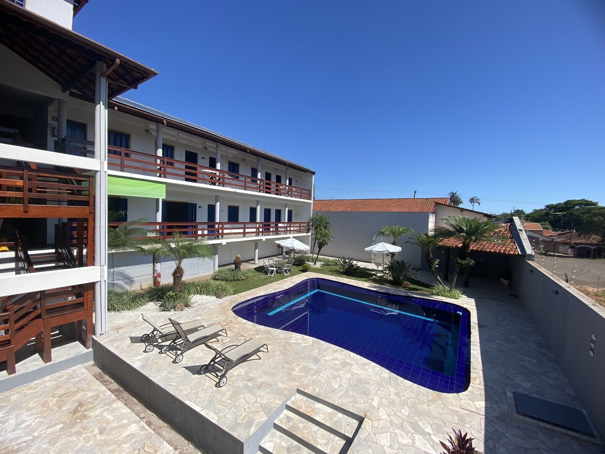 Un hotel con piscina, mobiliario exterior y zona ajardinada.