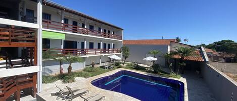 A hotel with a swimming pool, outdoor seating, and a garden area.