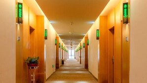 A long, well-lit hotel corridor with doors on both sides, each marked with a green sign indicating room numbers. - Greentree Inn Hefei Binhu New District Ziyun Road and Qingtan Road Jianghuai Car Factory (Hefei)