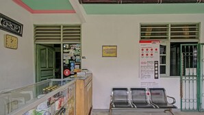A reception area with a counter displaying various items, a wall clock, and a bench. - OYO 3724 Penginapan Baiti Jannati Syariah (Banjarbaru)