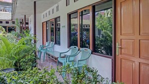 A covered outdoor seating area with plastic chairs and tables, surrounded by potted plants. - OYO 3724 Penginapan Baiti Jannati Syariah (Banjarbaru)