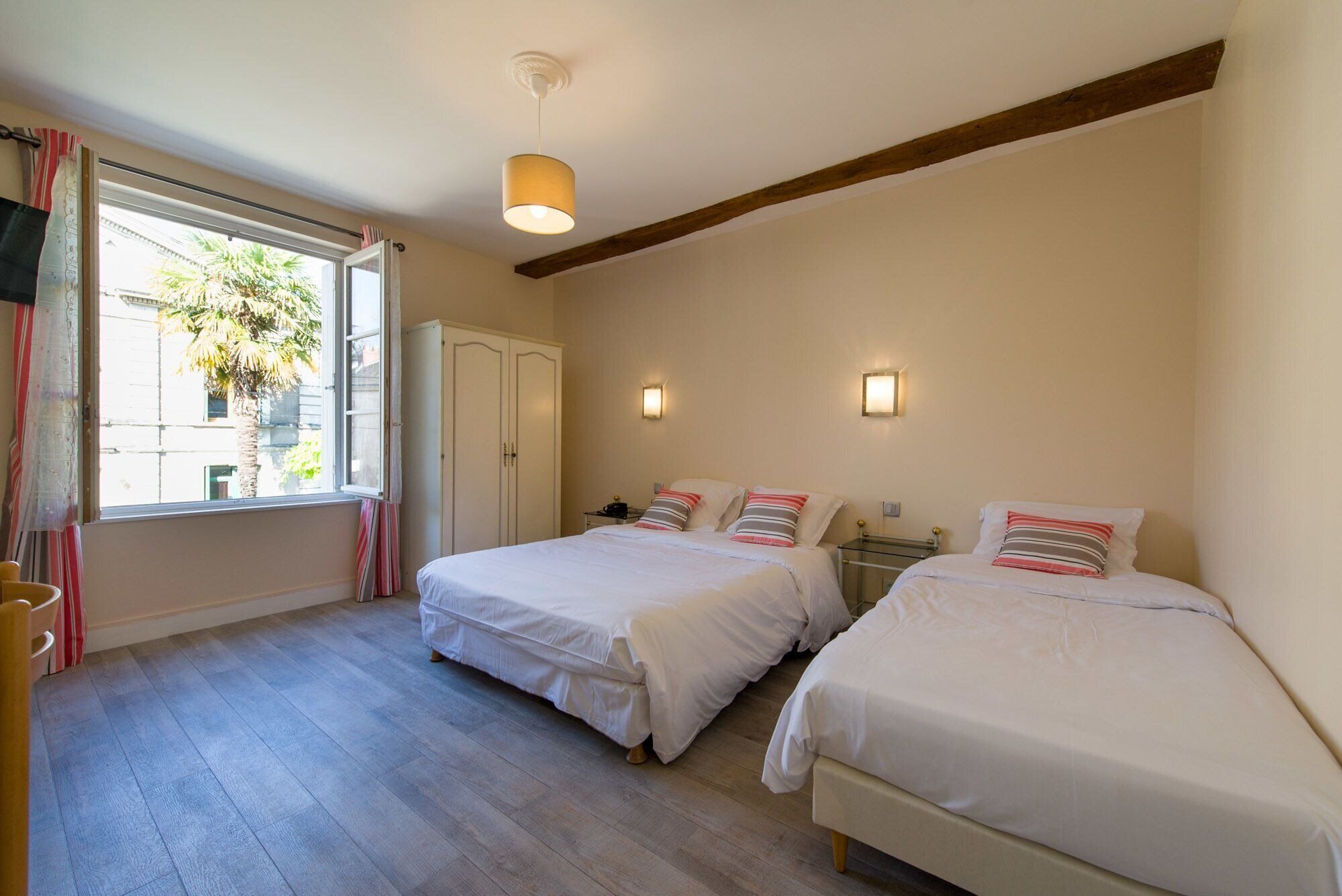 Ein Schlafzimmer mit zwei Betten, einem Schrank, einem Schreibtisch und einem Fenster mit Vorhängen.