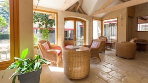A sunlit room with wicker furniture, large windows, and a tiled floor. - Hotel Val De Loire (Azay-le-Rideau)