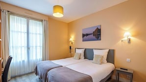 A double bed with a headboard, two bedside tables, a desk with a chair, and a window with curtains. - Hotel Val De Loire (Azay-le-Rideau)