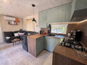 Cocina compacta con isla integrada, cafetera y ventana con vistas.
