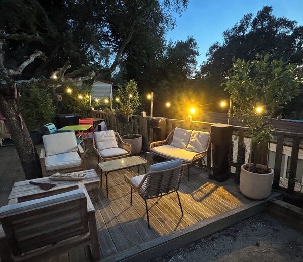 An outdoor patio with wooden furniture, string lights, and potted plants.