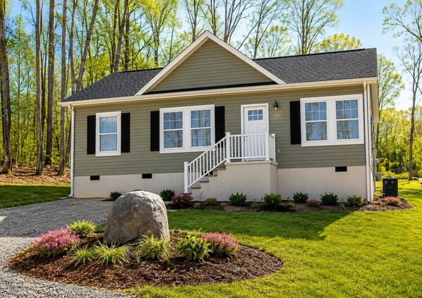 A single-story house with a front porch, a staircase, and a well-maintained lawn.
