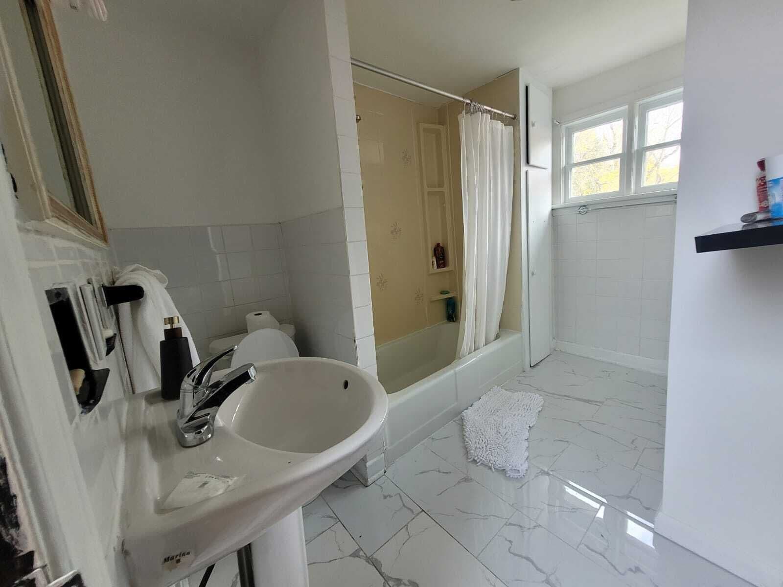Un baño con lavamanos blanco, bañera y zona de ducha.