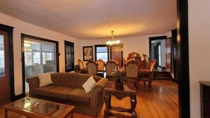 A living room with a sofa, coffee table, dining table with chairs, and a chandelier. - Lakeview Cottage in Roseneath (Roseneath)