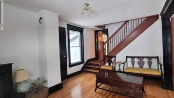 A staircase with wooden railings and a bench, a door leading to another room, and a lamp on a table.