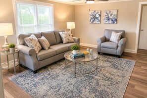 A living room with a sofa, armchair, coffee table, and two lamps.