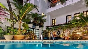 A pool area with a clear view of the pool, surrounding plants, and a building with balconies. - Casa Sirena 8 Bedroom in Centro Villa with Pool, Walk Everywhere, Group Ready (Isla Mujeres)