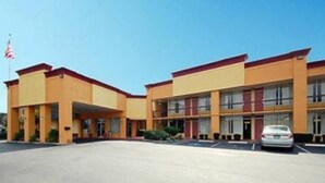 Ein Hotel mit zwei Etagen, einer flachen Dachkonstruktion und einem Parkplatz davor.